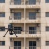 Drone scanning the grid-like facade of a balconied apartment building during a facade inspection