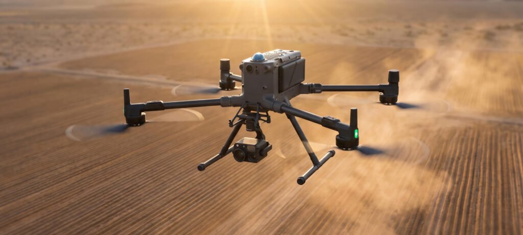 This photograph showcases the DJI Matrice 350 RTK commercial-grade quadcopter drone performing an automated flight mission over a dusty, agricultural or desert terrain.